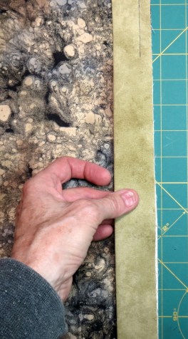 Pinch all four layers of the binding tails between your thumb and forefinger